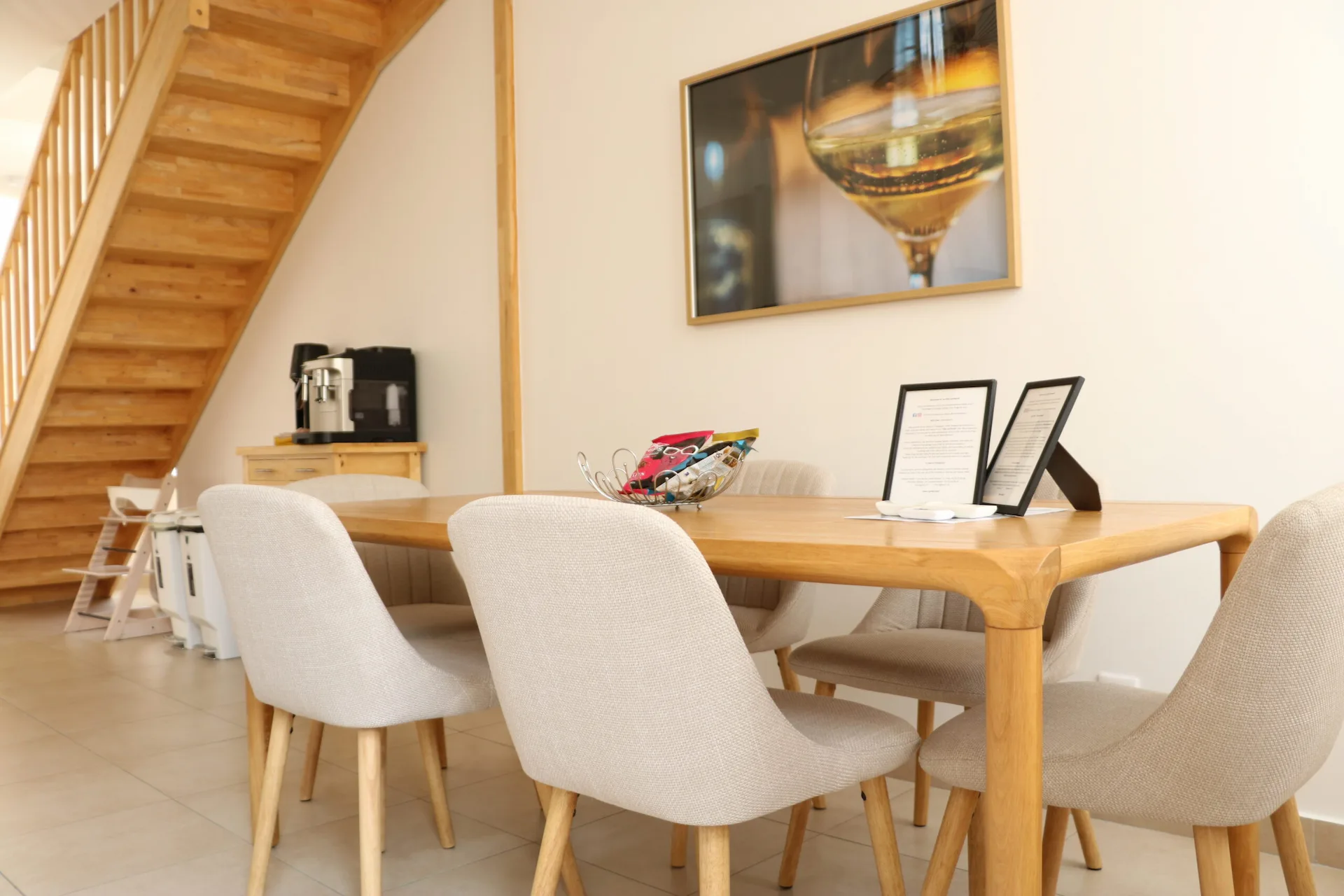 Salle à manger de La Villa Lombardi aux Riceys, avec table en bois, fauteuils et escalier en bois.
